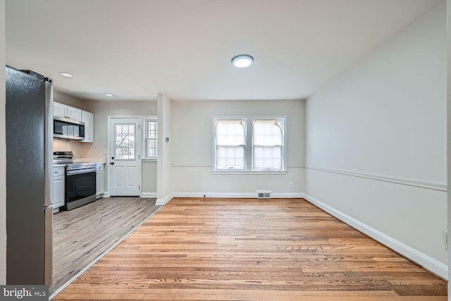 kitchen featuring white cabinetry, light hardwood / wood-style flooring, plenty of natural light, and appliances with stainless steel finishes