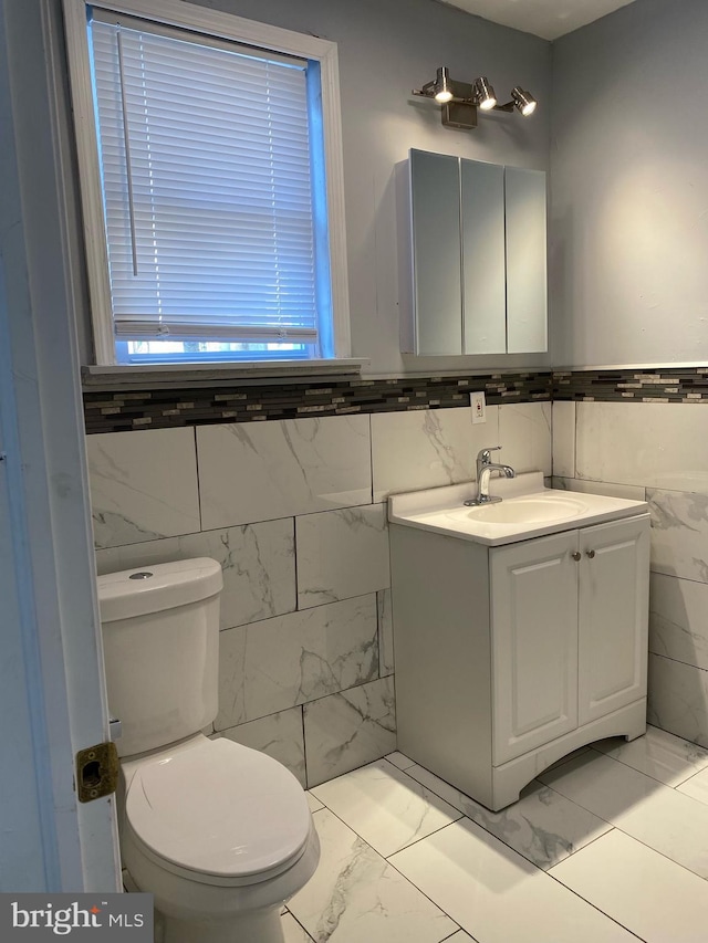 bathroom featuring vanity, tile walls, and toilet