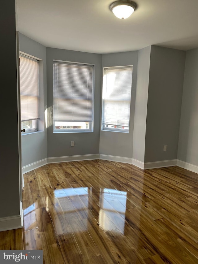 empty room with plenty of natural light and hardwood / wood-style floors