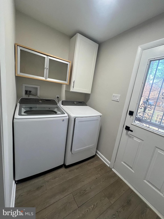 clothes washing area with cabinet space, baseboards, washer and clothes dryer, and dark wood-style flooring