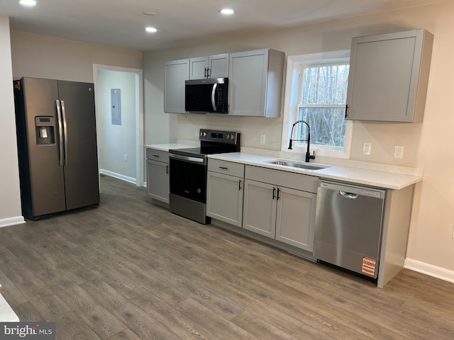 kitchen featuring stainless steel appliances, light countertops, a sink, and gray cabinetry