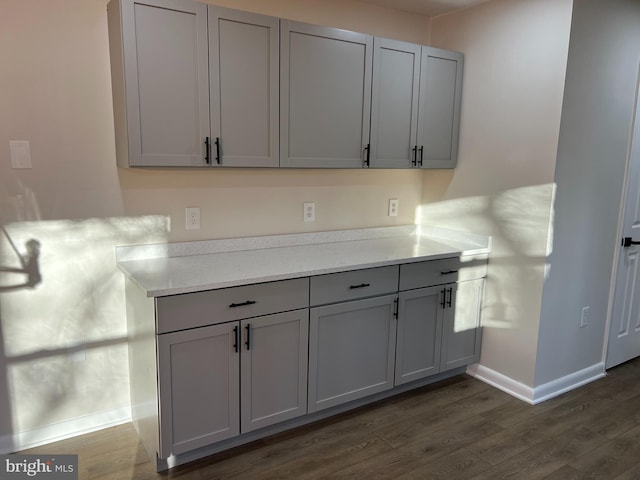 kitchen with dark wood-style floors, gray cabinets, baseboards, and light countertops