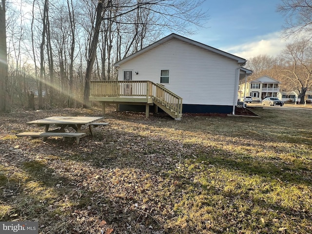 back of property featuring a deck, a yard, and stairs