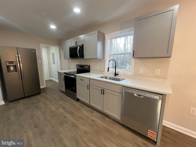 kitchen featuring stainless steel appliances, light countertops, a sink, and dark wood-style floors