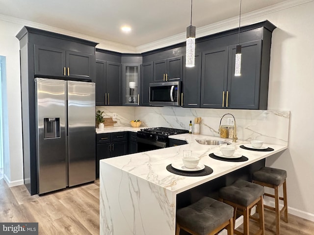 kitchen featuring appliances with stainless steel finishes, decorative light fixtures, tasteful backsplash, sink, and light hardwood / wood-style flooring