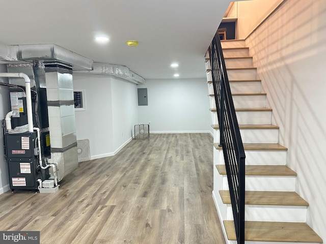 basement featuring wood-type flooring, heating unit, and electric panel