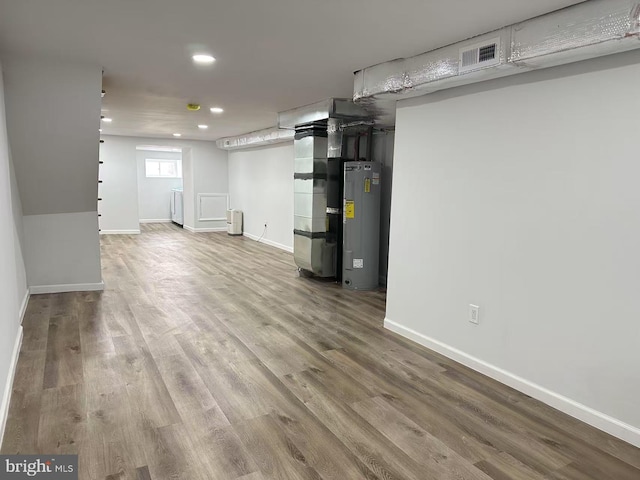 basement with water heater, wood-type flooring, washer / dryer, and heating unit