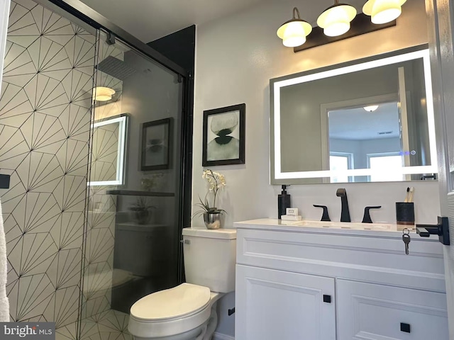 bathroom with vanity, a shower with shower door, and toilet