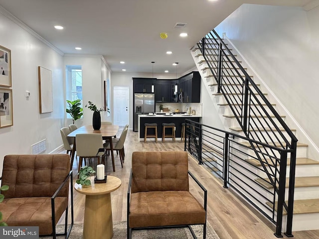 living room with crown molding and light hardwood / wood-style flooring