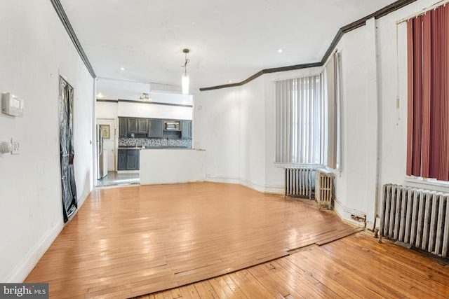 unfurnished living room featuring radiator heating unit, ornamental molding, and light wood-type flooring