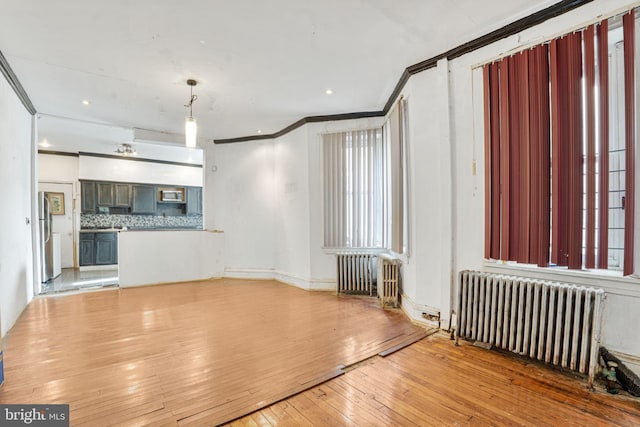 unfurnished living room with crown molding, radiator heating unit, and light hardwood / wood-style floors