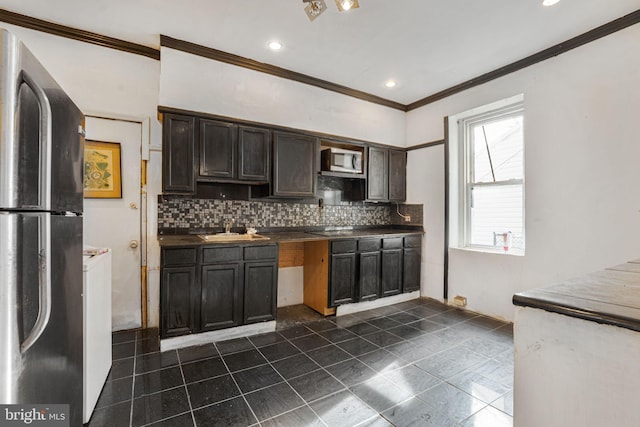 kitchen featuring black fridge, stainless steel microwave, sink, and backsplash