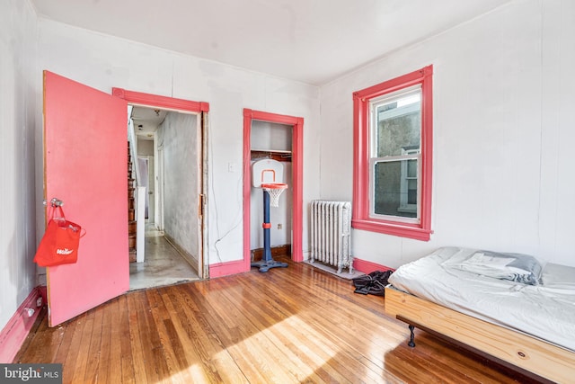 bedroom with radiator, hardwood / wood-style floors, and a closet