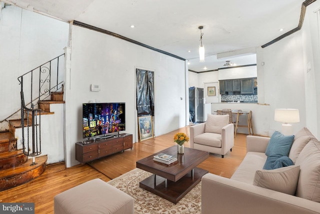 living room with crown molding and light wood-type flooring