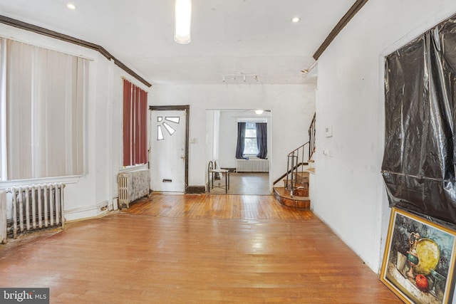 entrance foyer featuring ornamental molding, radiator heating unit, and wood-type flooring