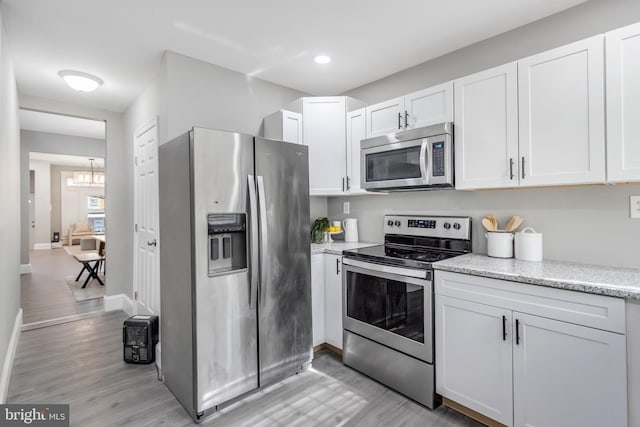 kitchen featuring appliances with stainless steel finishes, light hardwood / wood-style flooring, and white cabinets