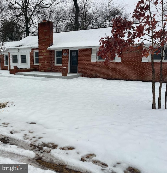 view of front of house featuring brick siding and a chimney