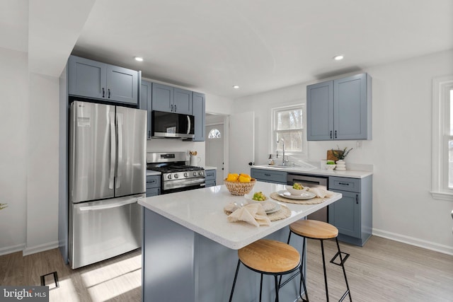 kitchen featuring light stone counters, a breakfast bar, a kitchen island, a sink, and appliances with stainless steel finishes