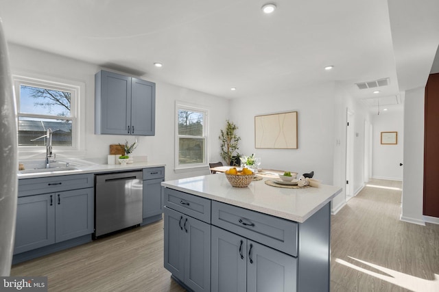 kitchen with light wood-type flooring, visible vents, a sink, and stainless steel dishwasher