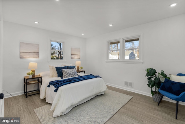 bedroom featuring multiple windows, light wood-type flooring, and visible vents