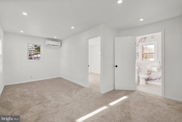 unfurnished bedroom featuring light colored carpet, a wall unit AC, baseboards, and recessed lighting