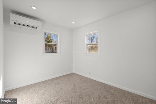 empty room featuring recessed lighting, a wall unit AC, carpet flooring, and baseboards