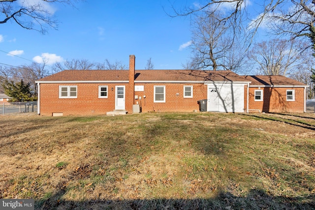 rear view of house with a garage, central AC unit, a lawn, fence, and brick siding