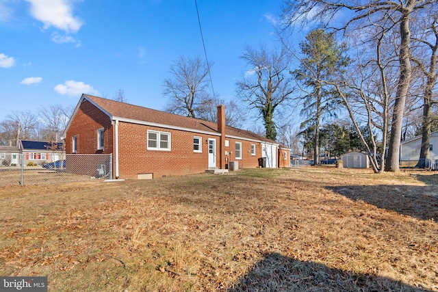 rear view of house with brick siding, a chimney, crawl space, fence, and a shed