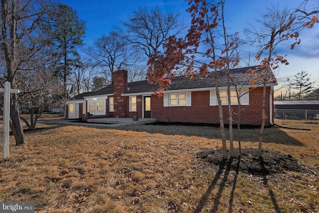 view of front of home featuring a front yard, a chimney, and brick siding