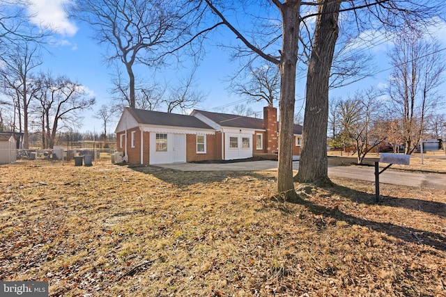 view of side of home with brick siding, fence, a yard, a chimney, and a patio area