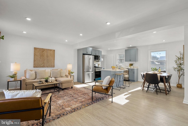 living area with baseboards, light wood finished floors, and recessed lighting