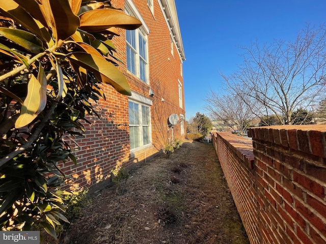 view of property exterior with brick siding and fence