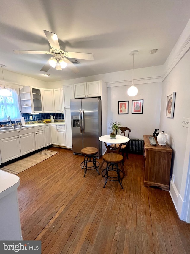 kitchen featuring white cabinetry, hanging light fixtures, stainless steel fridge, and sink