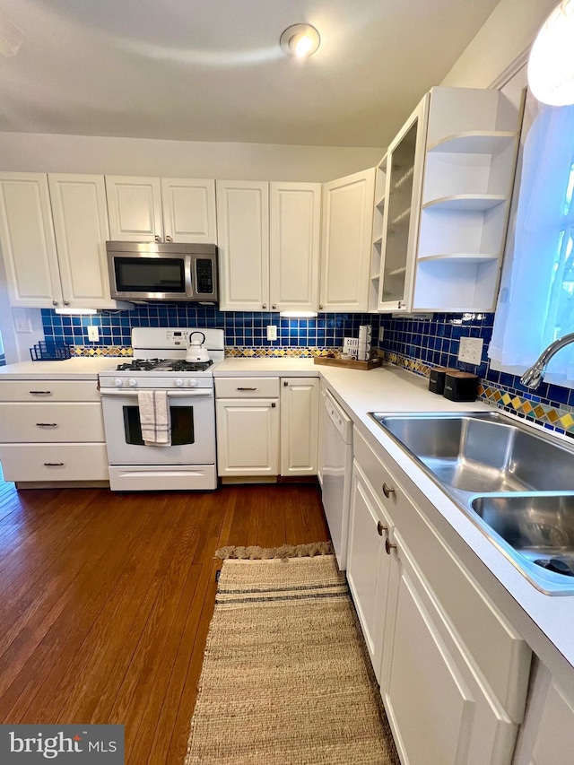 kitchen with sink, white cabinetry, dark hardwood / wood-style flooring, white appliances, and decorative backsplash