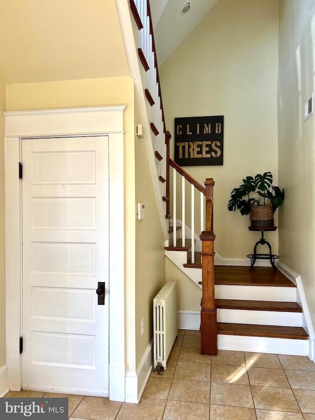 staircase with lofted ceiling, radiator, and tile patterned floors