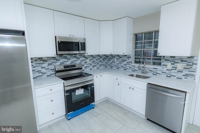 kitchen featuring white cabinetry, stainless steel appliances, sink, and light stone counters