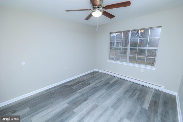 empty room with a baseboard heating unit, ceiling fan, baseboards, and wood finished floors