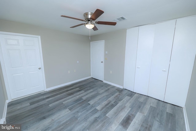 unfurnished bedroom with ceiling fan, wood finished floors, visible vents, and baseboards