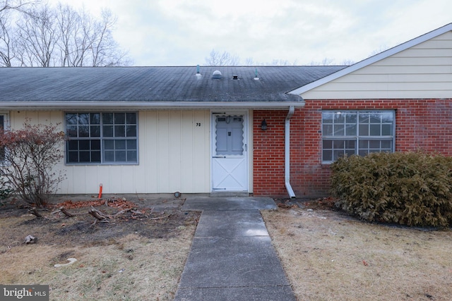 property entrance with brick siding and a shingled roof