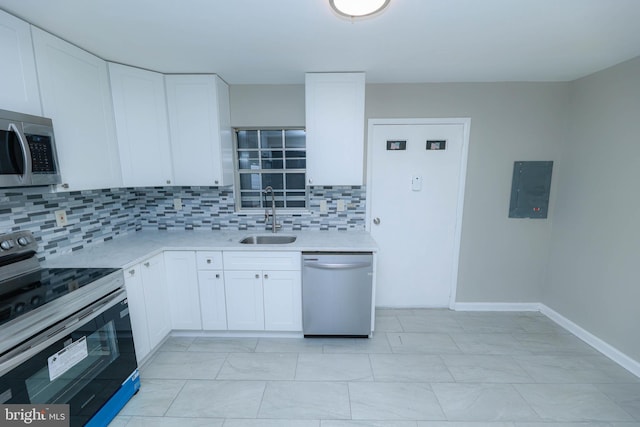 kitchen featuring stainless steel appliances, a sink, white cabinets, electric panel, and tasteful backsplash