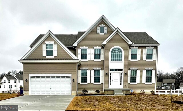 colonial-style house with a garage, driveway, and fence