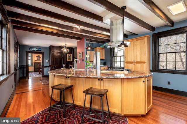 kitchen with light stone counters, stainless steel refrigerator with ice dispenser, baseboards, and wood finished floors