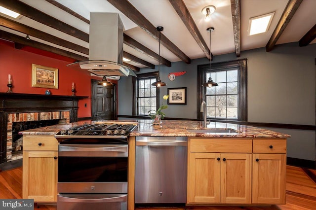 kitchen with stainless steel appliances, dark stone countertops, a sink, and island range hood