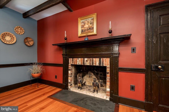 interior space with a brick fireplace, baseboards, and wood finished floors