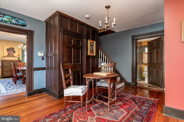 dining area featuring wood finished floors, stairway, and an inviting chandelier