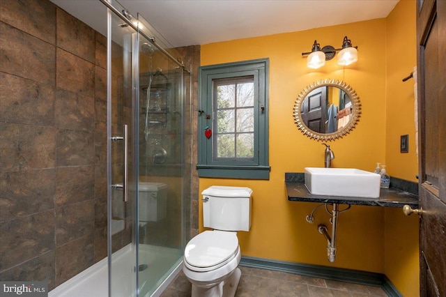 bathroom with a stall shower, baseboards, a sink, and toilet