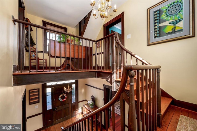 stairway with a chandelier, baseboards, and hardwood / wood-style floors