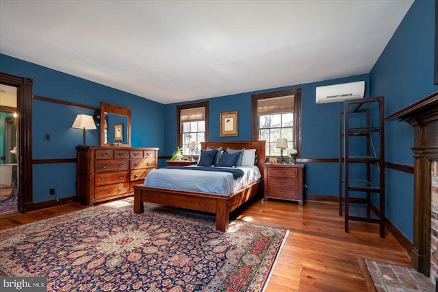 bedroom with wood-type flooring, baseboards, and an AC wall unit