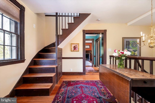 staircase with baseboards, an inviting chandelier, and wood finished floors