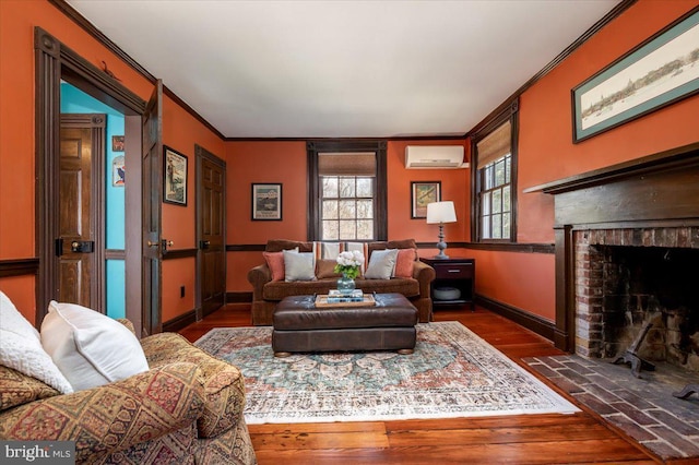 sitting room featuring a fireplace, wood finished floors, baseboards, an AC wall unit, and crown molding